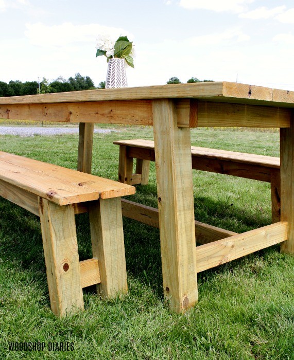 Close up of stained outdoor trestle table and bench design sitting out in front yard