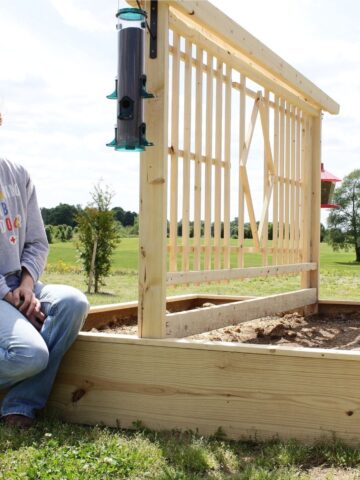 Shara sitting on edge of DIY garden bed with trellis