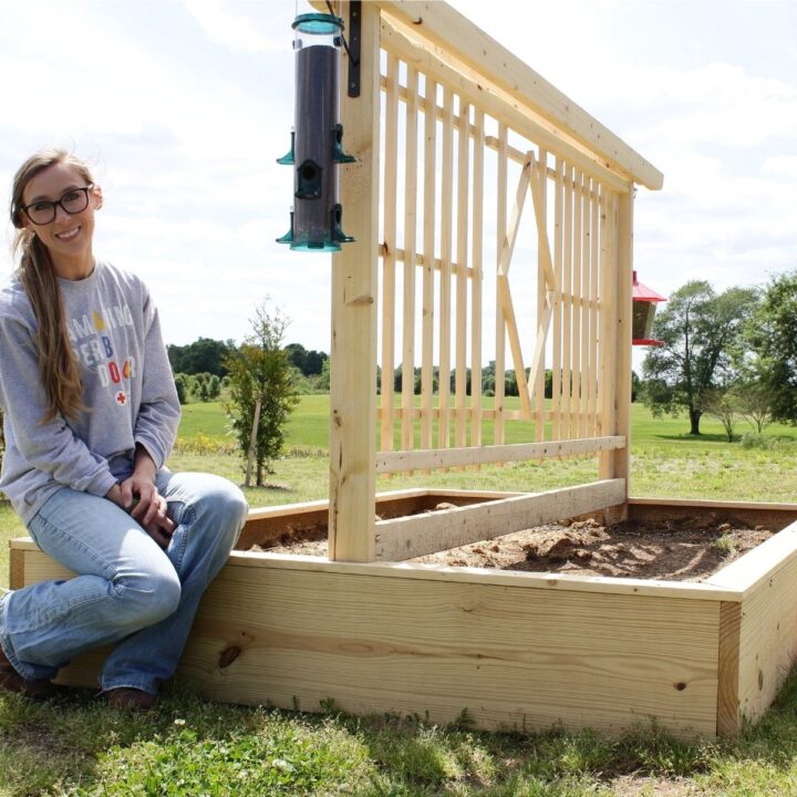 Shara sitting on edge of DIY garden bed with trellis