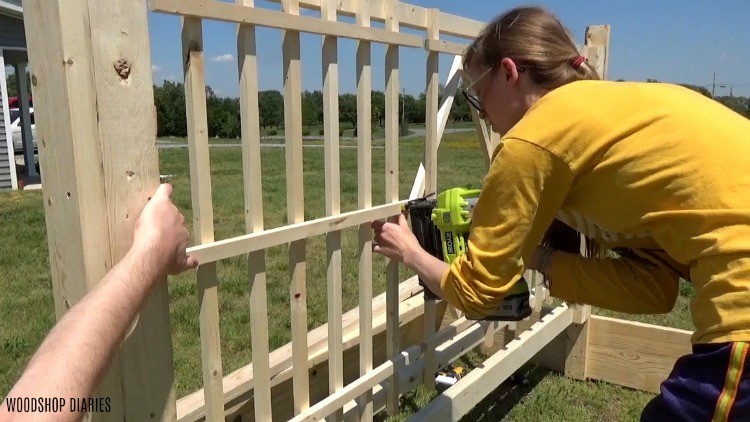 Nailing pieces of garden bed trellis in place with a nail gun