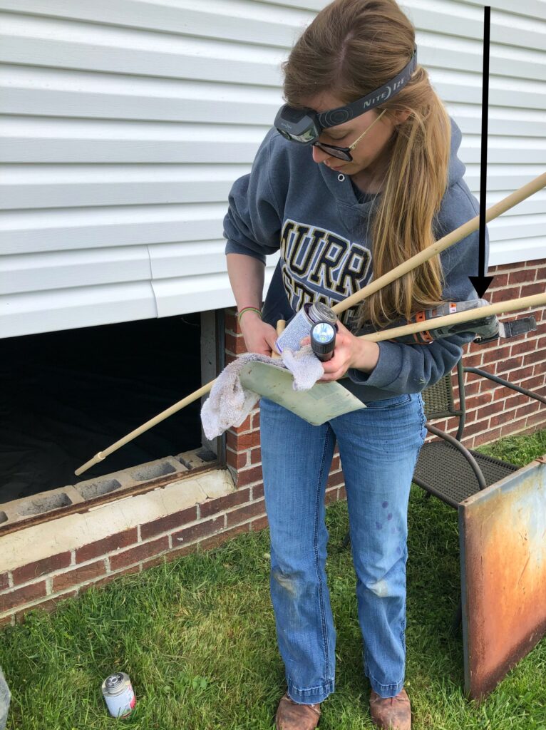 Shara using oscillating saw to cut pluming pipes under house in bathroom remodel