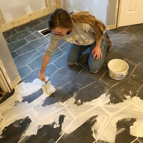 Shara grouting floor tile in master bathroom