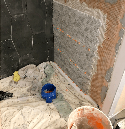 Herringbone tile installed on right side of shower wall
