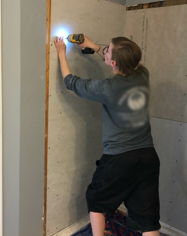 Shara installing cement board into shower nook for tile walls