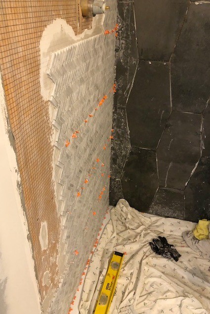 Herringbone tile installed on left side of shower wall