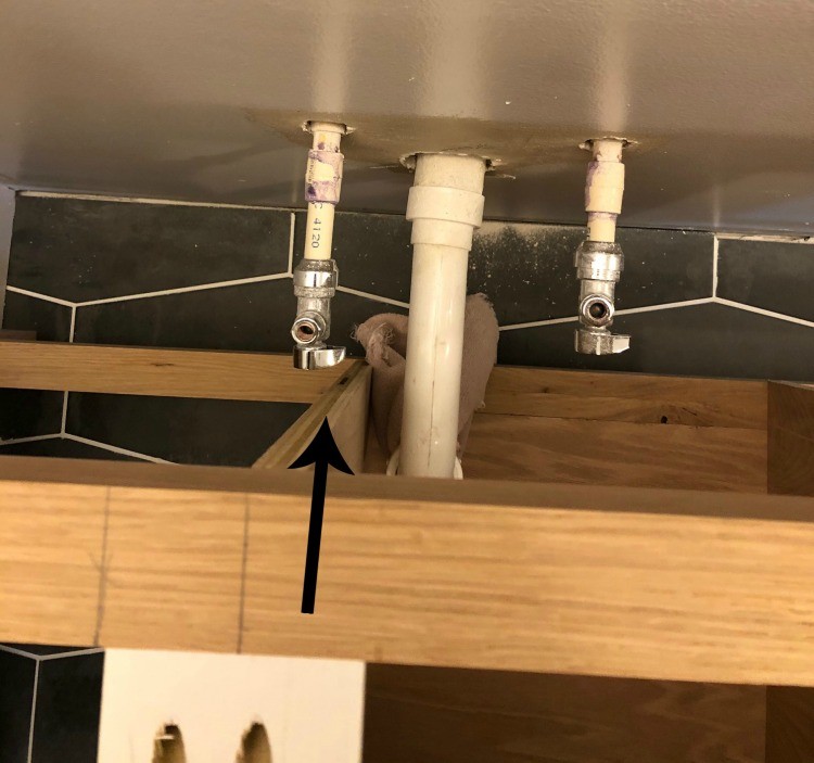 Plumbing pipe lined up perfectly with divider panel in master bathroom vanity
