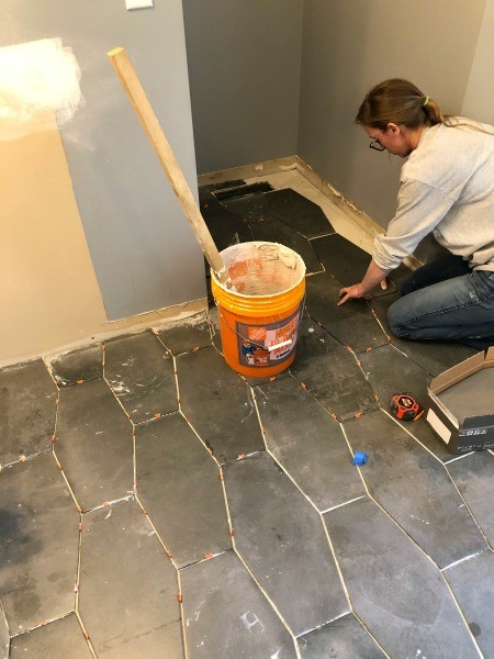 Shara tiling master bathroom floor into back corner