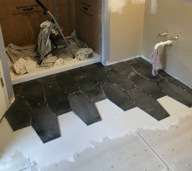 First two and three rows of master bathroom renovation floor tile starting out from shower