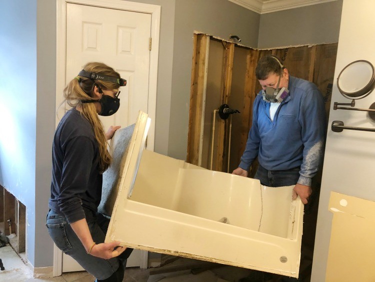 Shara and Dad carrying out old shower stall in pieces