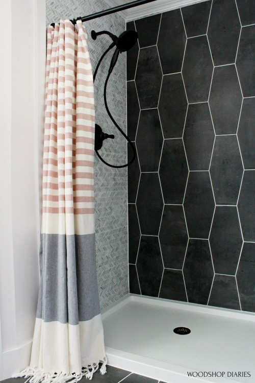 Copper and grey CB2 shower curtain against light and dark grey shower walls and white shower pan