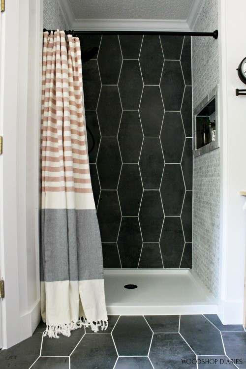 Up close master bathroom shower tile--dark grey back wall and light grey side walls with copper and grey curtain