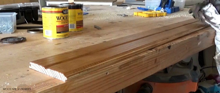 Shara using a rag to apply stain to a pine board on workbench
