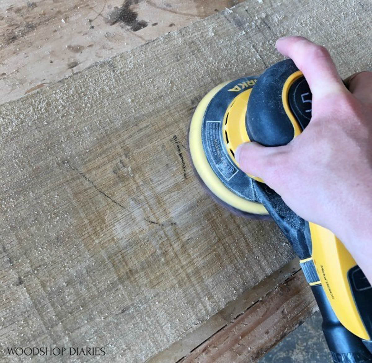 sanding a piece of wood with a palm sander