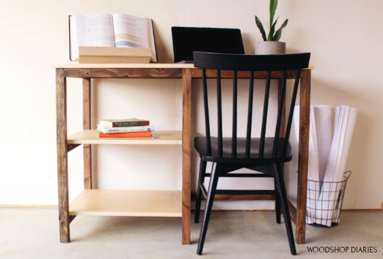 Simple DIY desk view from the front with small black chair pushed up and laptop open on top of desk