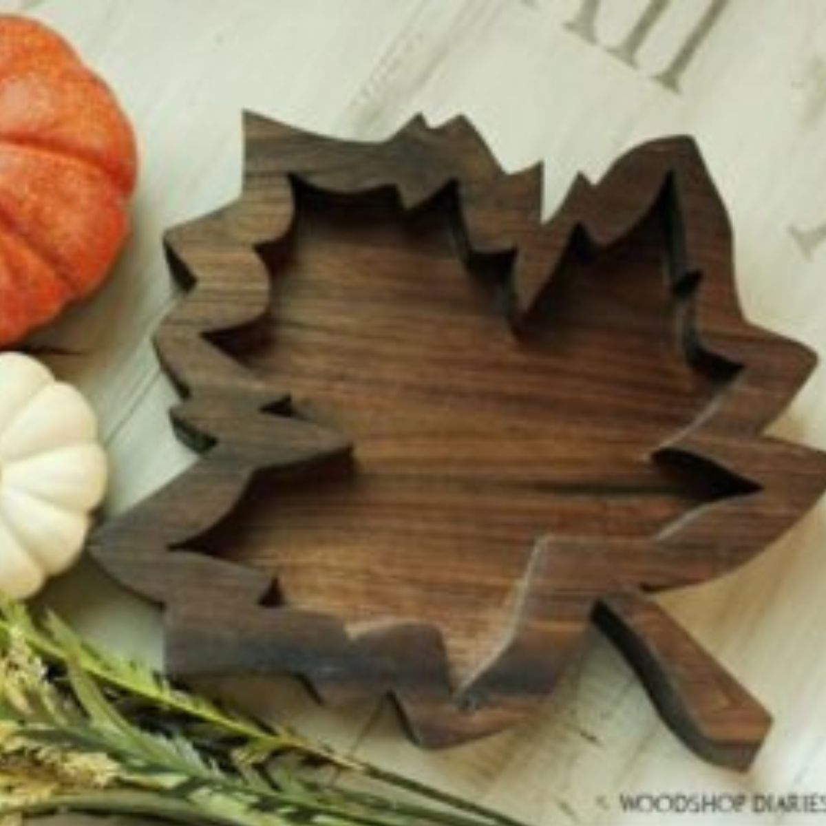 Completed fall tray sitting on coffee table with orange and white pumpkins and fall greenery.