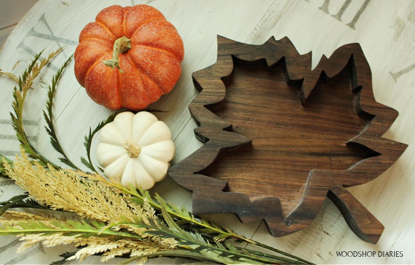 Completed fall tray sitting on coffee table with orange and white pumpkins and fall greenery.