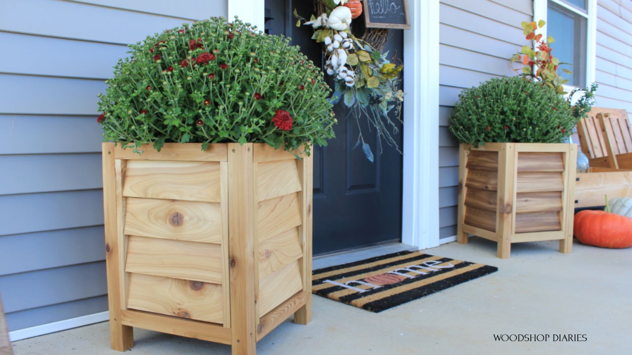 DIY Louvered Cedar Planters on each side of black front door with red mums
