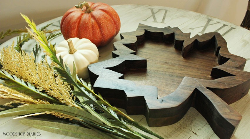 Completed fall tray sitting on coffee table with orange and white pumpkins and fall greenery.