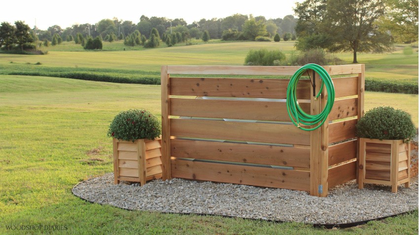 Wide angle view of simple fake fence used to cover and hide outdoor eye sore of a well house