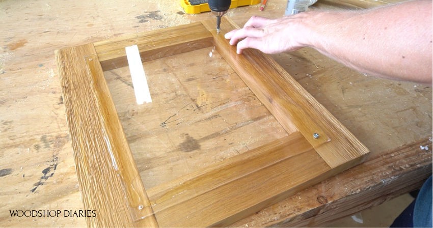 Screwing plexiglass panel to donation box door frame