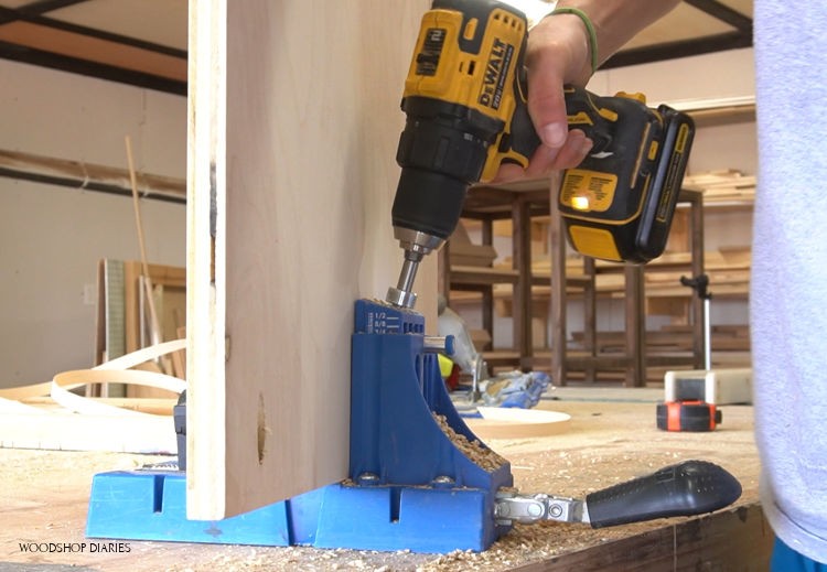 Plywood clamped in pocket hole jig with drill drilling holes