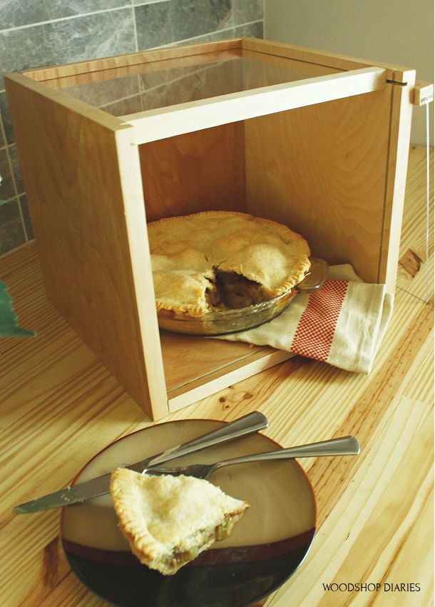 DIY Scrap Wood and plexiglass pie and cake carrier display box with front piece open and a slice of apple pie cut