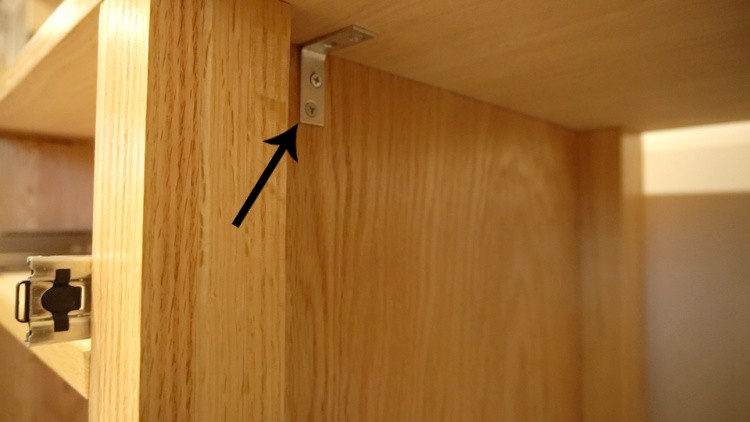 Using corner brackets to secure L shaped desk top