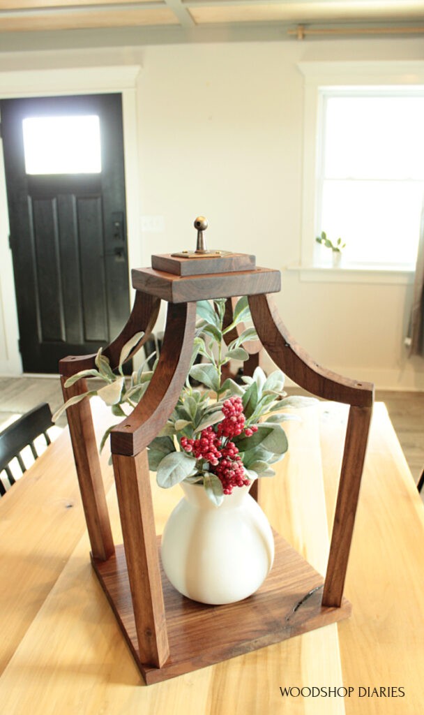 Close up of DIY scrap wood lantern with vase and flower arrangement inside