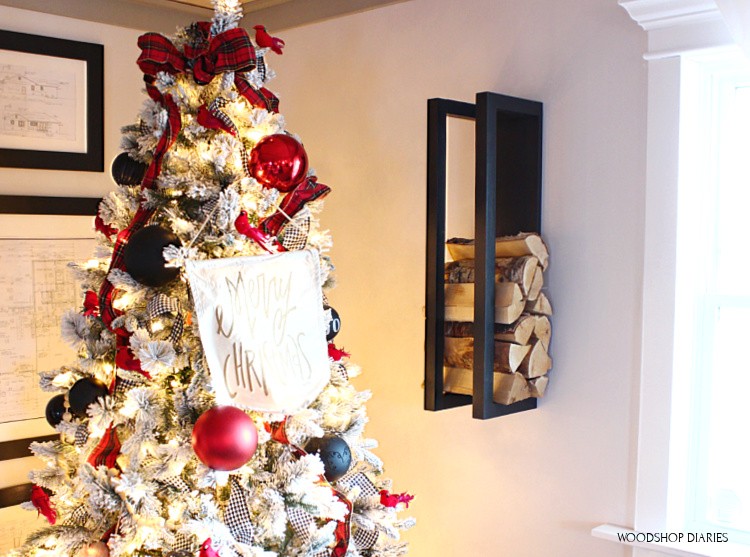 DIY scrap wood firewood rack hanging on wall next to Christmas tree