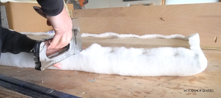 Stapling batting along bottom of bench seat to upholster