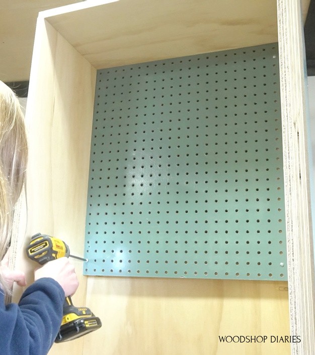 Screw peg board panel onto cabinet