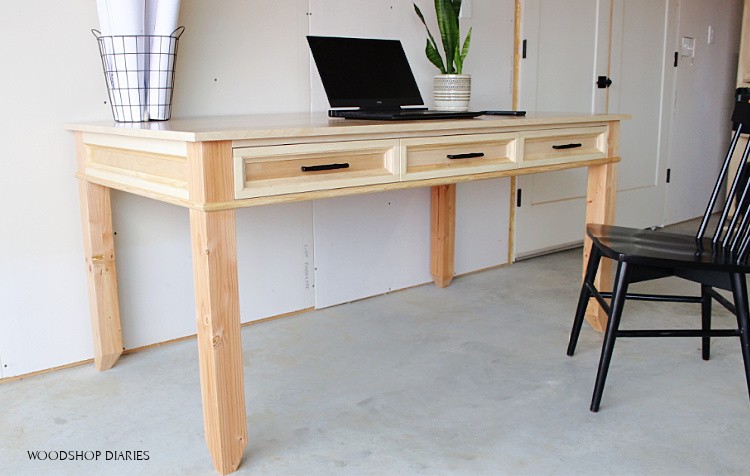 Basic DIY writing desk finished and staged with black chair and laptop--Simple pine desk