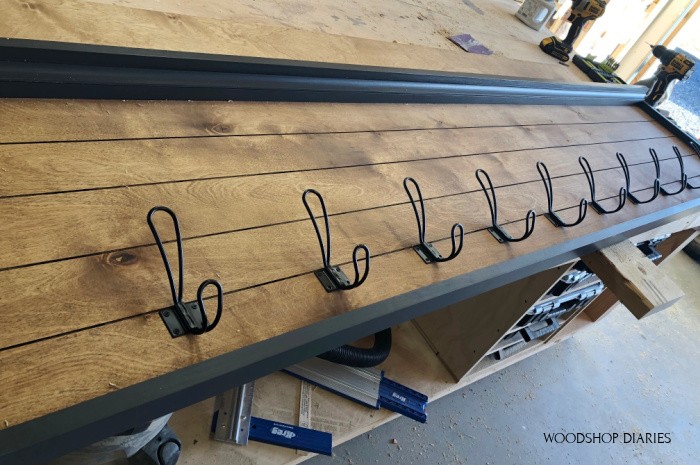 Large black hooks evenly spaced and attached along back coat rack panel