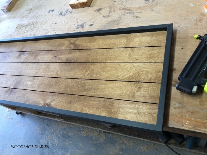 Stained back panel with black 1x2 frame nailed in place along sides