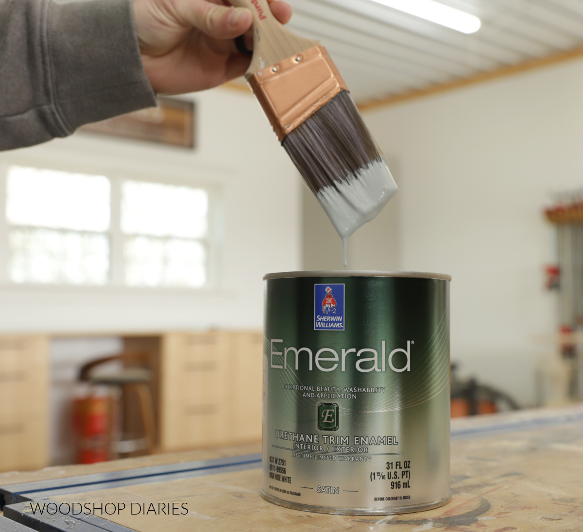 Close up of paintbrush dripping into paint can