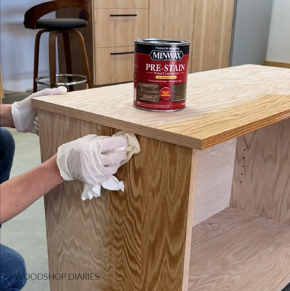 Shara Woodshop Diaries applying Minwax wood conditioner to oak cabinet with rag