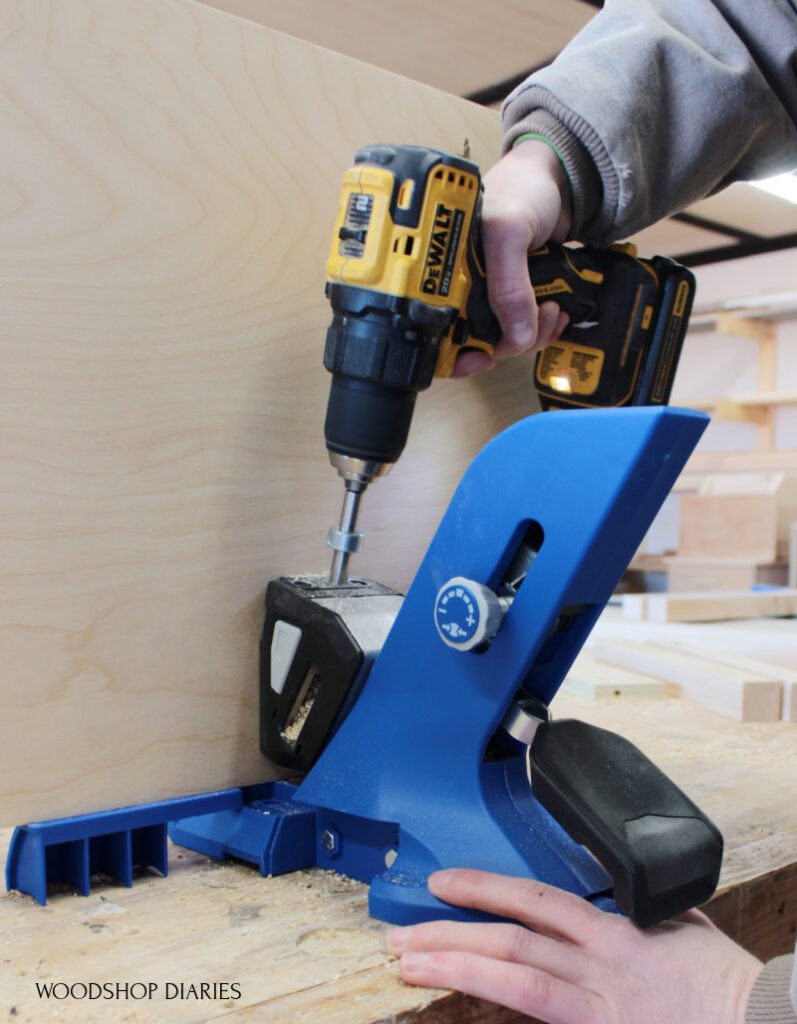 Shara using Kreg 720 pocket hole jig to drill holes in plywood panel