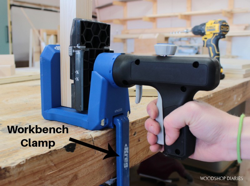 Kreg 520 clamped to workbench with pocket hole clamp and hand clamping the trigger