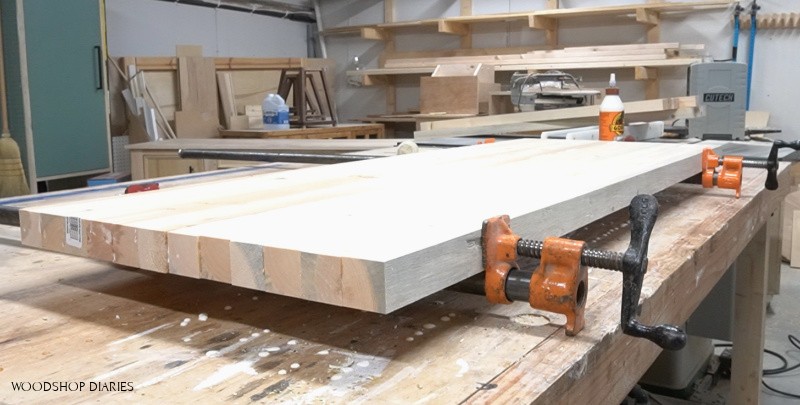 Panel in pipe clamps on workbench being glued together