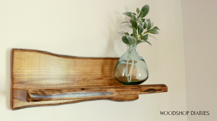 DIY Faux Live Edge Shelf made from pine wood hanging on wall with a glass vase