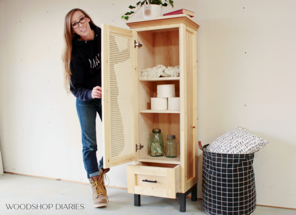 Shara holding tall linen cabinet door open to show what's inside