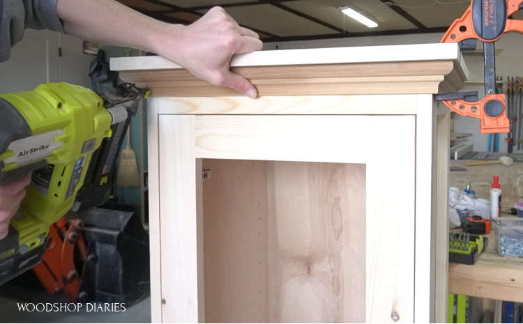 using nail gun to attach crown molding along top edge of linen cabinet