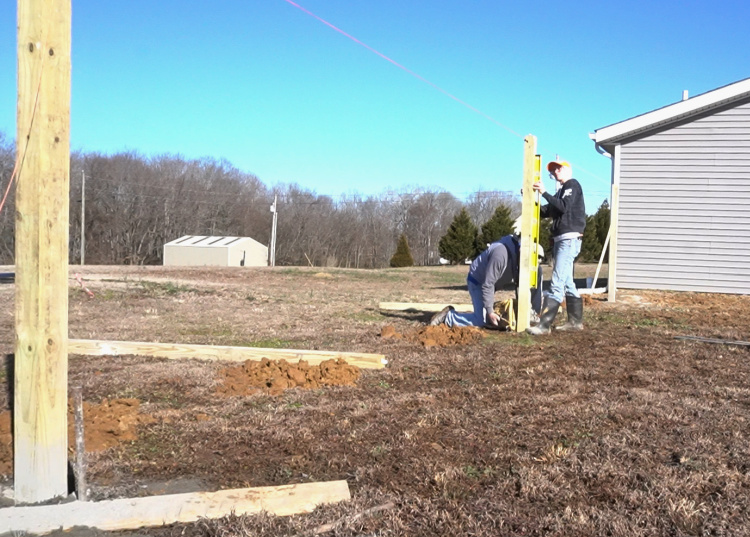 Installing fence posts into post holes and leveling with concrete mix