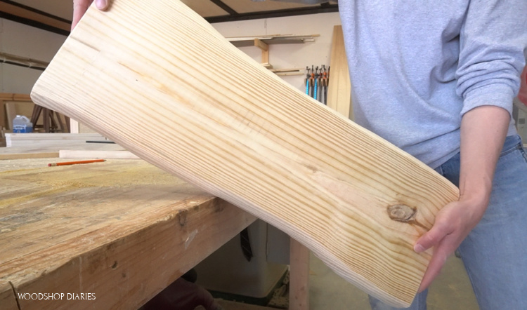 Shara Woodshop Diaries holding DIY faux live edge pine board with edges carved using angle grinder