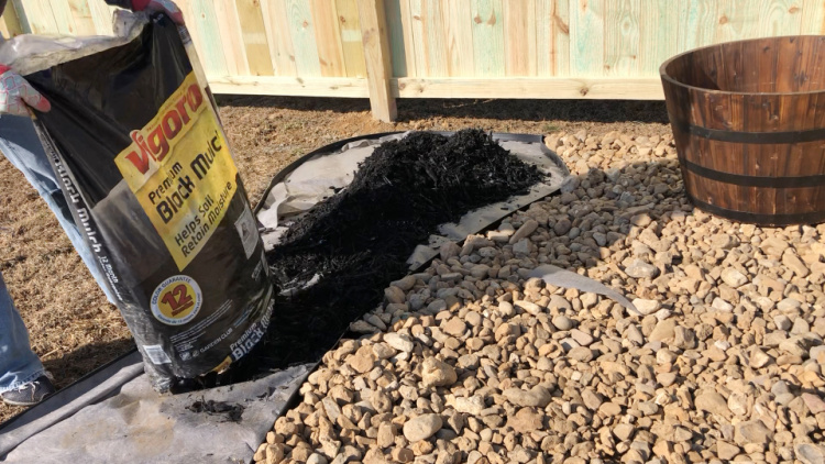 Shara dumping bag of black mulch in outside section of garden space in backyard makeover