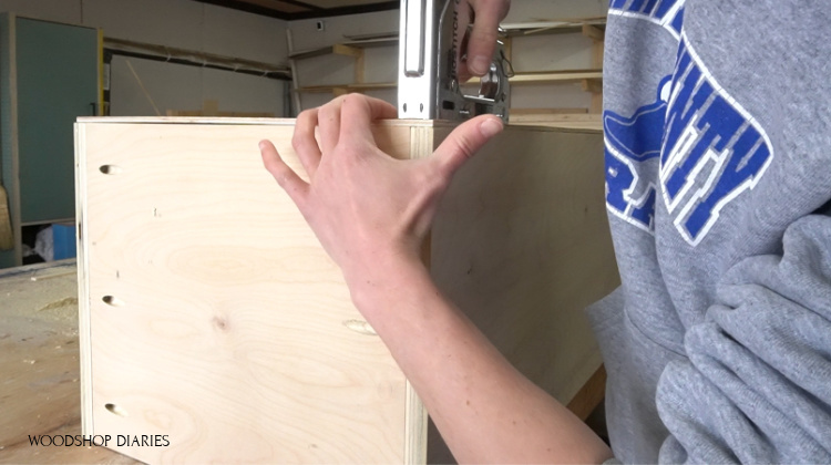 Stapling back panel in place on linen cabinet