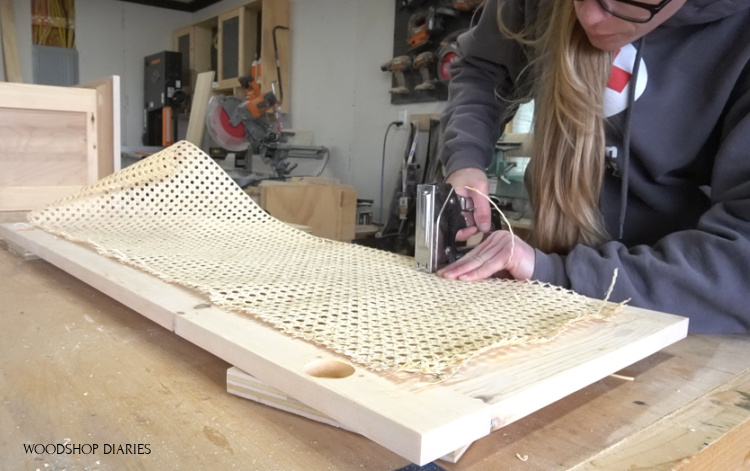 using staple gun to attach cane webbing to back side of cabinet door