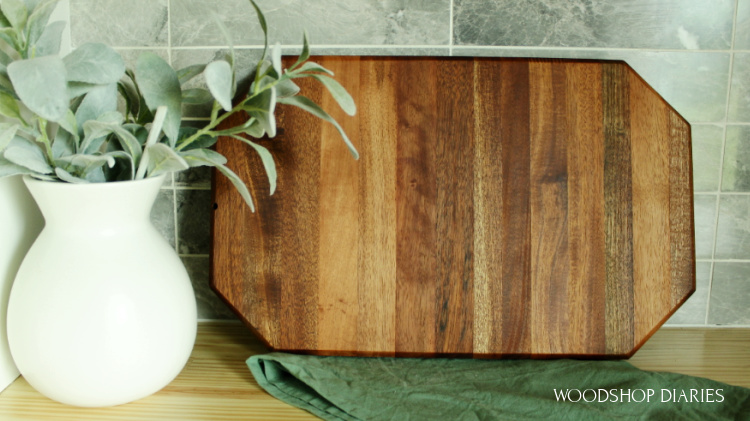 DIY Mahogany cutting board made from old front door leaning against tile backsplash on countertop