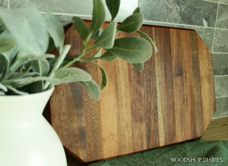 Finished cutting board on countertop leaning against backsplash