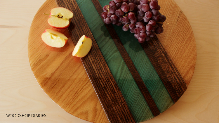 Overhead view of red oak multicolored DIY wood and epoxy lazy susan with apples and grapes on top